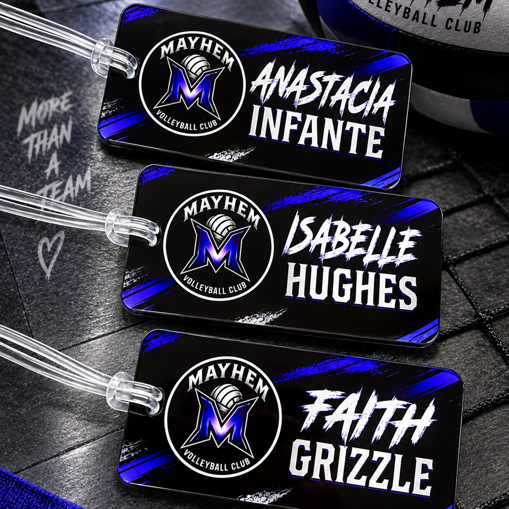 Three custom black volleyball-themed luggage tags with clear plastic loops, featuring the Mayhem Volleyball Club logo and player names Anastacia Infante, Isabella Hughes, and Faith Grizzle. A matching black, white, and blue volleyball is partially visible in the top right corner.