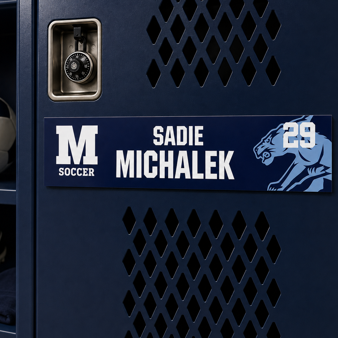 A close-up of a navy blue soccer locker with a custom nameplate reading 'SADIE MICHALEK' and the number '29', alongside a large 'M SOCCER' logo and a panther graphic. A soccer ball and cleats are visible on the shelf to the left.