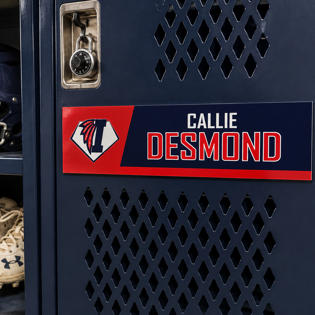 A close-up of a navy blue metal locker door with a custom nameplate reading CALLIE DESMOND in white and red, alongside an Illinois 'I' logo. Inside the locker, a navy helmet with an 'I' logo, white cleats, and a yellow softball are stored on shelves.